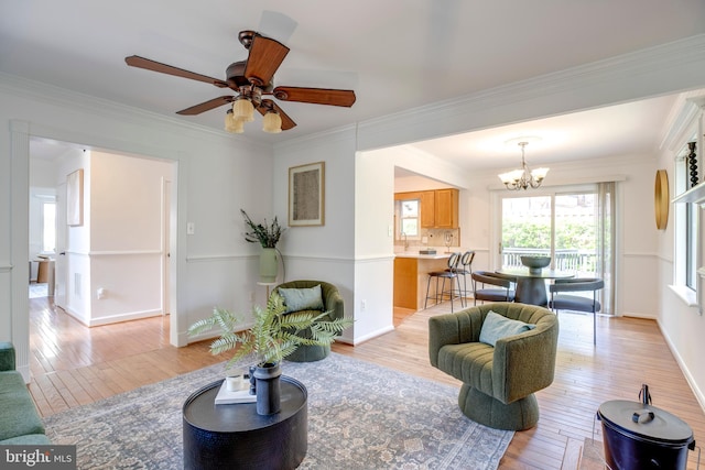 living room with light wood finished floors, ceiling fan with notable chandelier, and crown molding