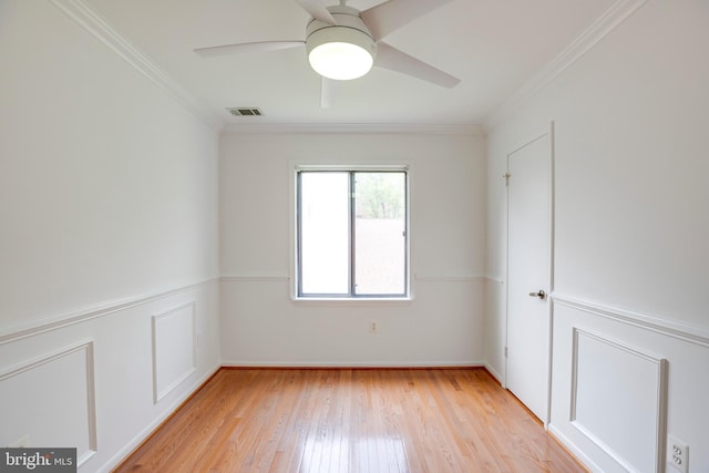 empty room with light wood finished floors, ceiling fan, ornamental molding, and visible vents
