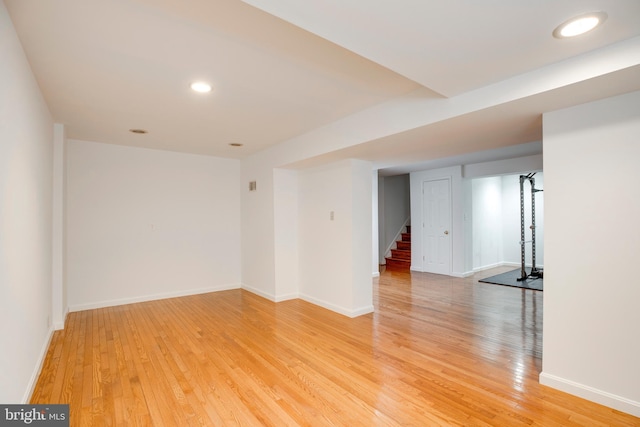 unfurnished room with stairway, light wood-style flooring, and baseboards