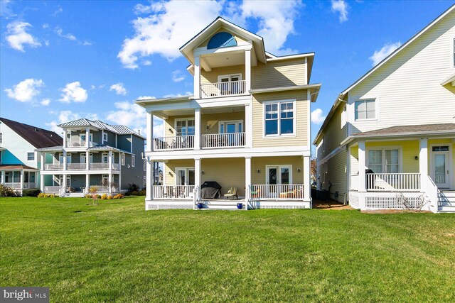 back of property featuring a lawn, french doors, a balcony, and a patio