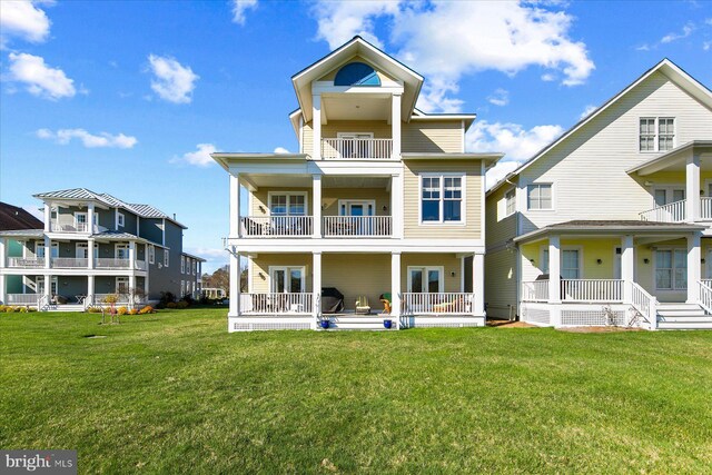 back of house featuring a lawn, a balcony, and french doors