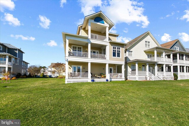 back of house with a lawn, a residential view, and a balcony