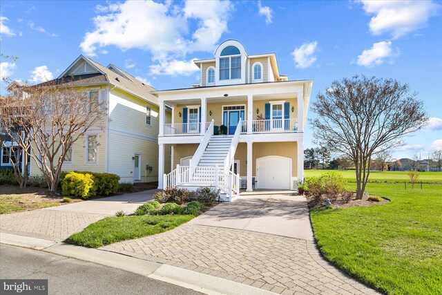 view of front of house with concrete driveway, covered porch, a front yard, a garage, and stairs