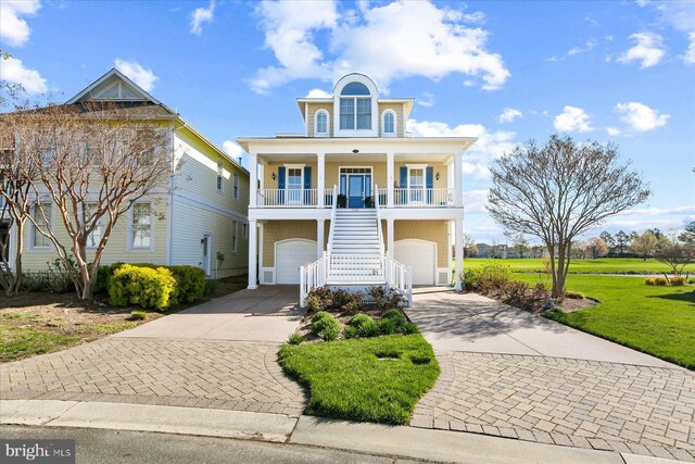 beach home featuring stairway, driveway, covered porch, a front yard, and a garage