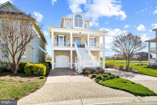 coastal home featuring a porch, a garage, stairway, and concrete driveway