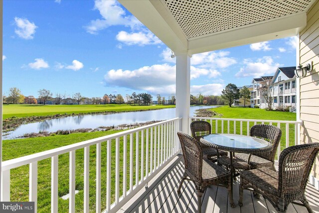 balcony featuring outdoor dining space and a water view
