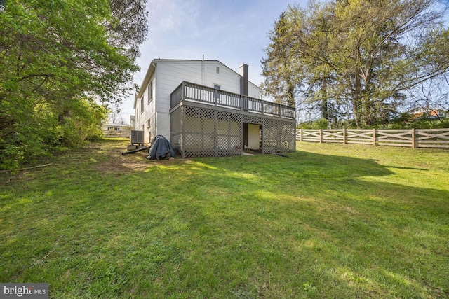 back of property featuring central air condition unit, a chimney, fence, a wooden deck, and a lawn