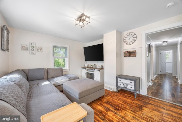 living area with baseboards, visible vents, and dark wood-style flooring