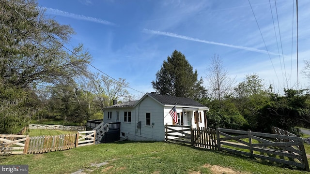 view of property exterior with a gate, a lawn, metal roof, and a fenced front yard