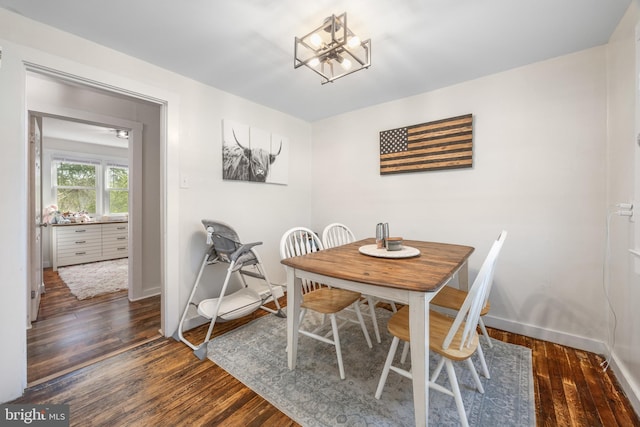 dining space with baseboards, a chandelier, and wood-type flooring