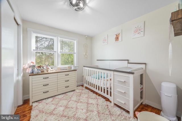 bedroom with a nursery area and wood finished floors