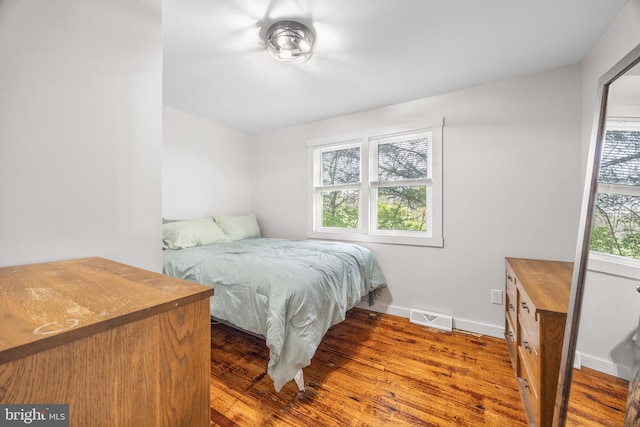 bedroom featuring baseboards, wood finished floors, and visible vents