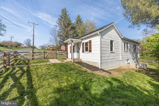 view of property exterior with a lawn, central AC unit, fence, and a gate