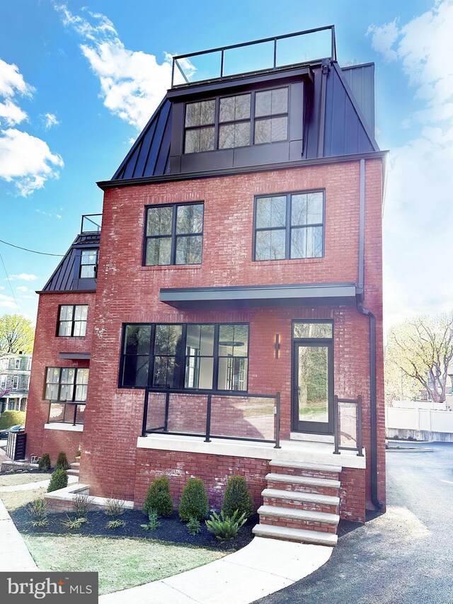 view of front facade featuring a standing seam roof, brick siding, and metal roof