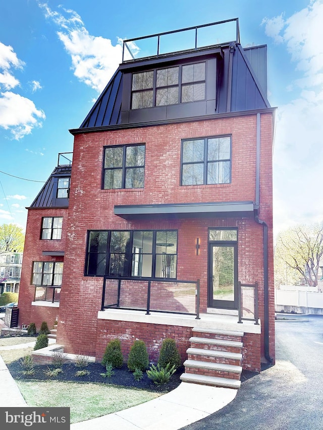 view of front facade featuring a standing seam roof, brick siding, and metal roof