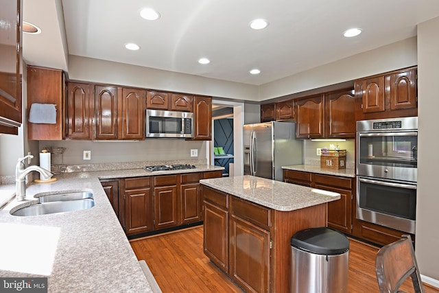 kitchen featuring dark wood finished floors, stainless steel appliances, a kitchen island, and a sink