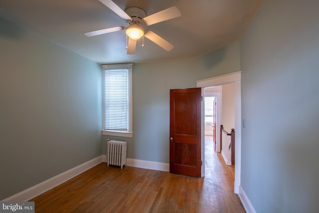 1323 W 41st St, Baltimore, MD 21211 - spare room featuring radiator heating unit, wood finished floors, baseboards, and a ceiling fan