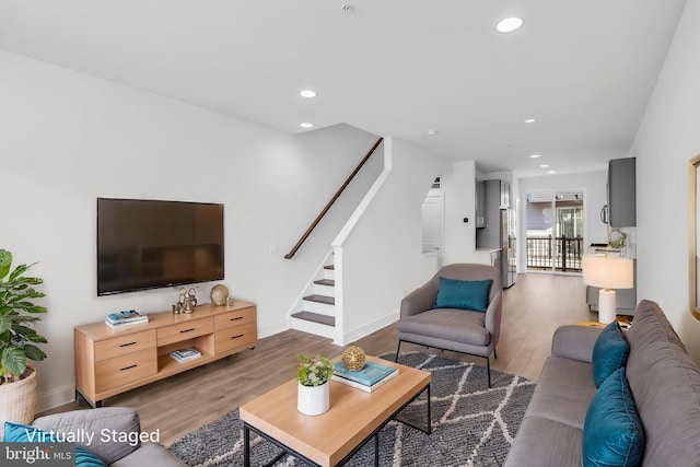 living area featuring wood finished floors, recessed lighting, baseboards, and stairs