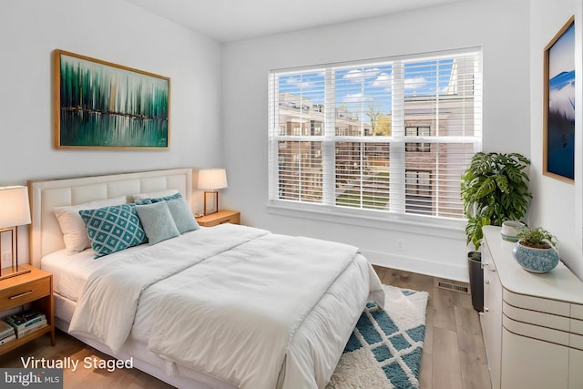 bedroom featuring wood finished floors, baseboards, multiple windows, and visible vents