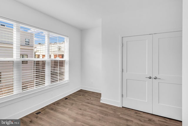 unfurnished room featuring wood finished floors, baseboards, and visible vents