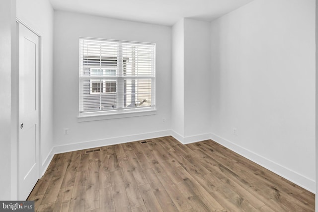 unfurnished room with visible vents, baseboards, and wood finished floors