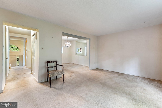 unfurnished room with light colored carpet, a chandelier, and baseboards
