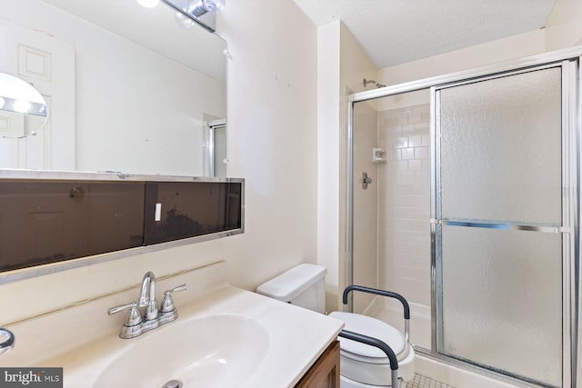 bathroom with toilet, a shower stall, vanity, and a textured ceiling
