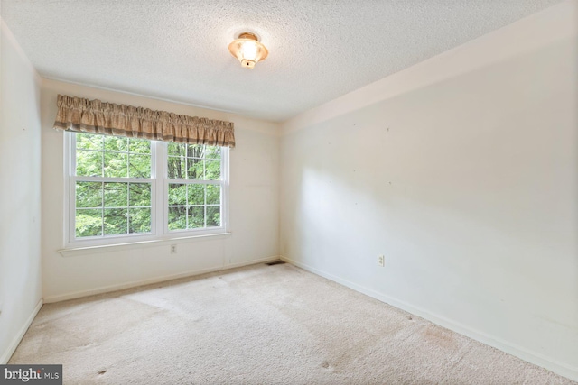 carpeted spare room with a textured ceiling and baseboards