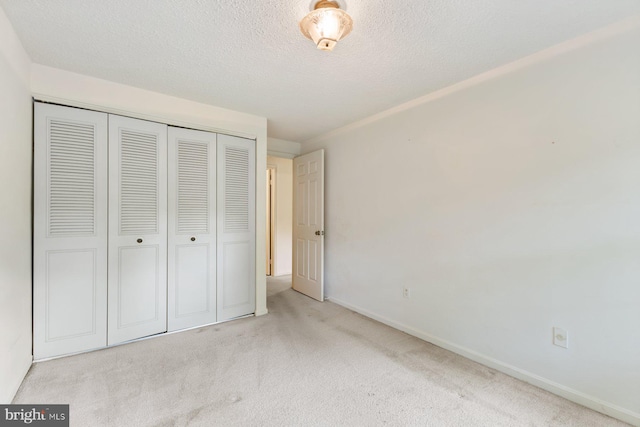 unfurnished bedroom featuring a closet, carpet floors, a textured ceiling, and baseboards