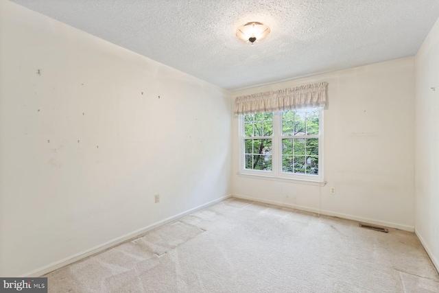 unfurnished room featuring a textured ceiling, carpet, and baseboards