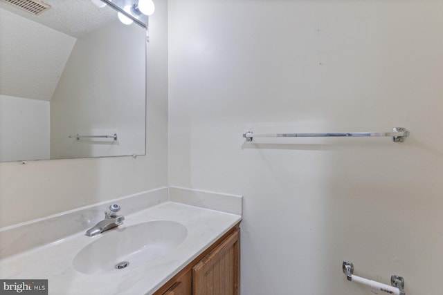 bathroom featuring vanity, lofted ceiling, and a textured ceiling