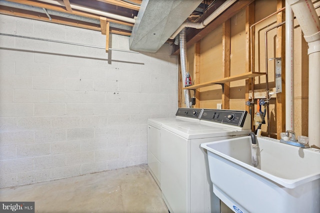 clothes washing area with washing machine and dryer and concrete block wall