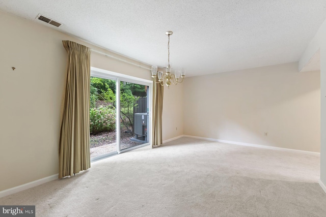 carpeted empty room featuring a chandelier, a textured ceiling, and baseboards