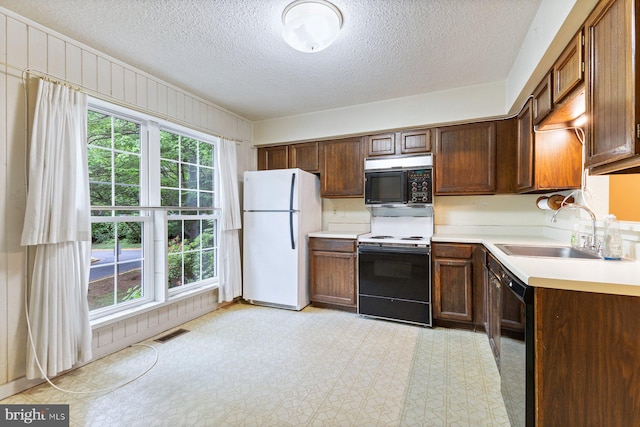kitchen with black appliances, a sink, a textured ceiling, plenty of natural light, and light countertops