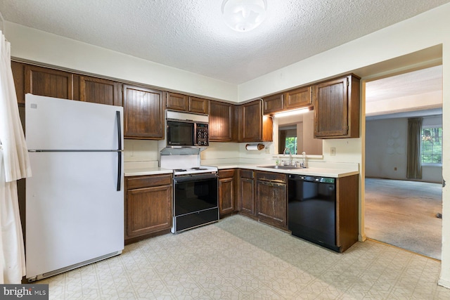 kitchen featuring freestanding refrigerator, stainless steel microwave, black dishwasher, range with electric stovetop, and a sink
