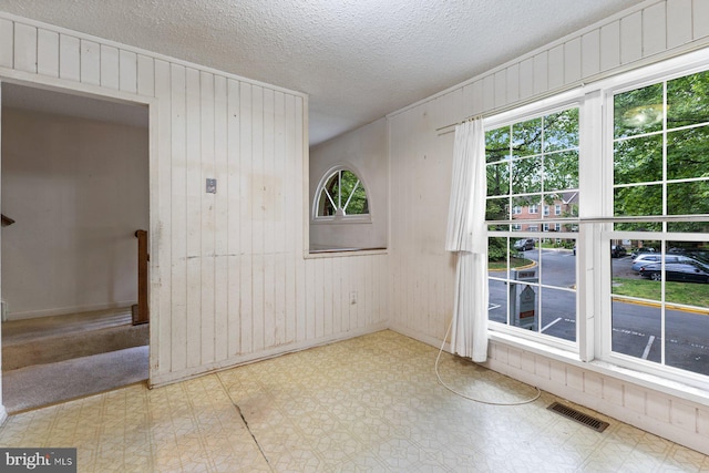 spare room with wooden walls, tile patterned floors, and a textured ceiling