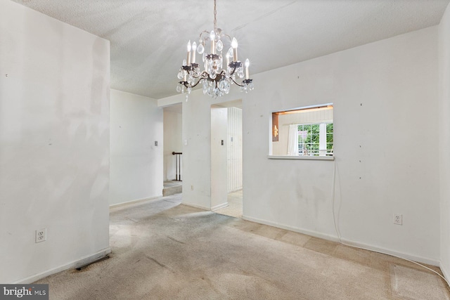 spare room with carpet, a chandelier, and baseboards