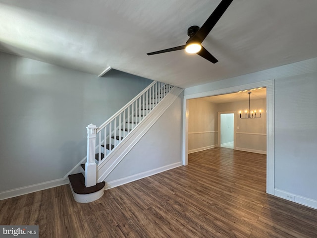 unfurnished living room with baseboards, stairs, ceiling fan with notable chandelier, and wood finished floors