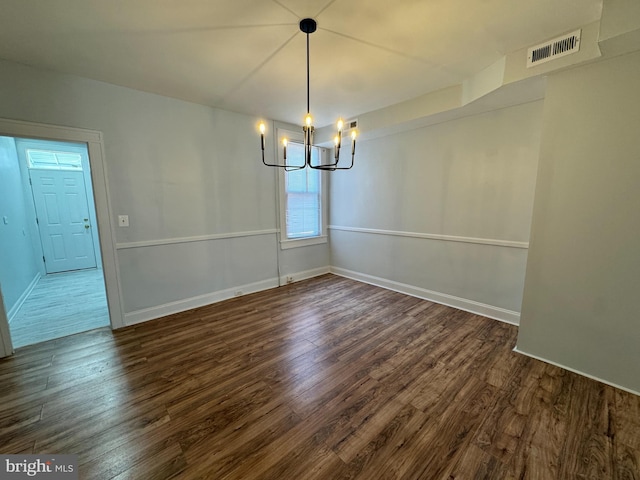 unfurnished dining area featuring baseboards, visible vents, dark wood-style floors, and a notable chandelier