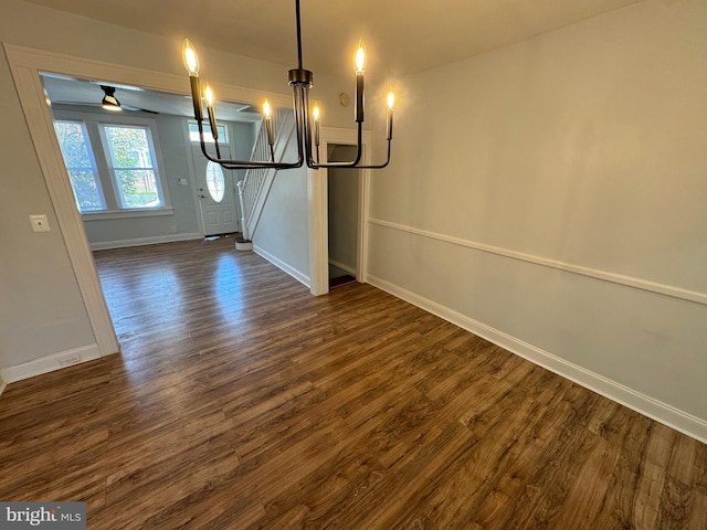 unfurnished dining area featuring an inviting chandelier, baseboards, and dark wood-type flooring