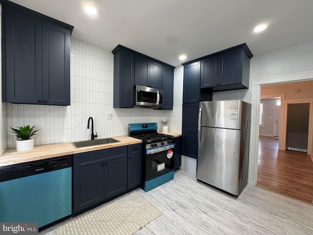 kitchen featuring a sink, tasteful backsplash, light wood-style floors, and stainless steel appliances