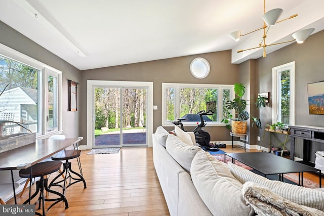 living area featuring baseboards, lofted ceiling, light wood-style flooring, and plenty of natural light