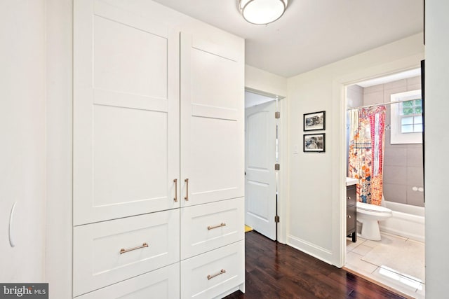 hallway featuring baseboards and dark wood-style flooring