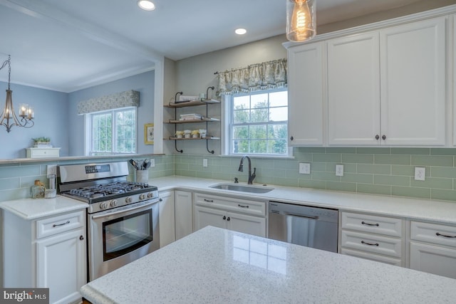 kitchen featuring a sink, appliances with stainless steel finishes, white cabinetry, light stone countertops, and decorative backsplash