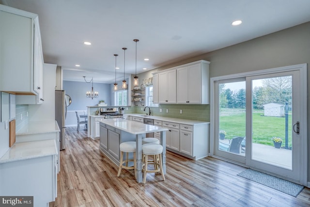 kitchen featuring light wood-style floors, tasteful backsplash, white cabinetry, appliances with stainless steel finishes, and a sink