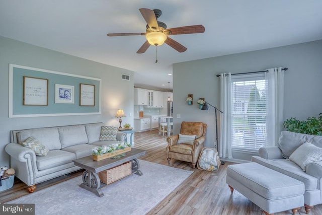 living room with visible vents, ceiling fan, and light wood finished floors
