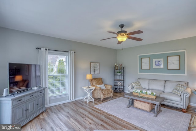 living room with light wood-type flooring, a ceiling fan, and baseboards
