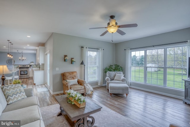 living room featuring baseboards, light wood-type flooring, recessed lighting, and a ceiling fan