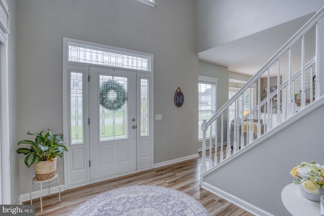 foyer entrance with wood finished floors, a high ceiling, baseboards, and stairway