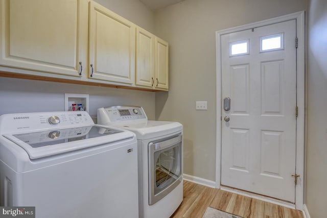 laundry room featuring light wood-type flooring, separate washer and dryer, baseboards, and cabinet space